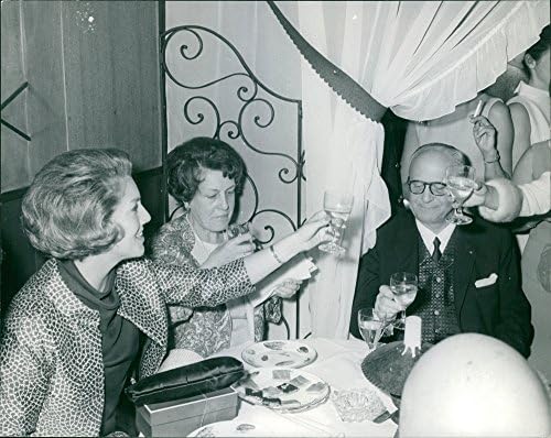 Foto vintage de James e Yvette de Rothschild brindando com outras pessoas.